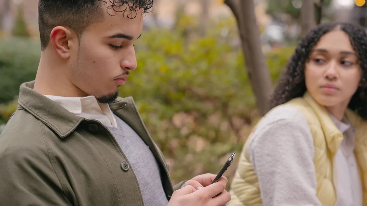 Telefon kullanan partnerine şüpheyle bakan kişi