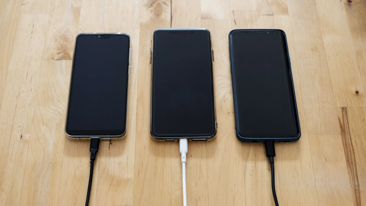 Yan yana duran ve kablolarla şarj edilen birden fazla telefon