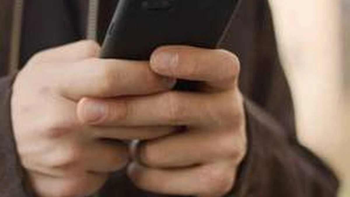 Elinde telefon tutan kişinin gizli mesajlaşma hissi veren yakın planı