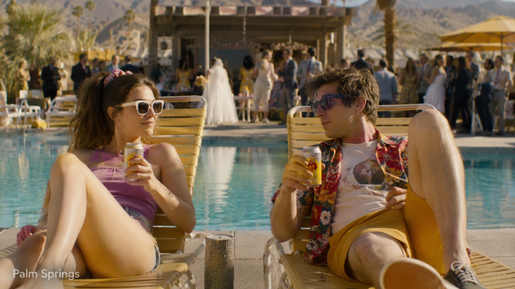 Palm Springs filminde havuz kenarında sohbet eden genç çift