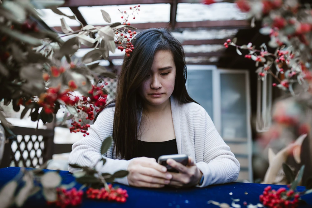 Telefonuna üzgün şekilde bakan kişi